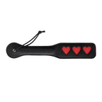 Paleta para nalgadas de color negro con diseño de corazón, marca juguitodecalzonco, cerrada y lista para usar.